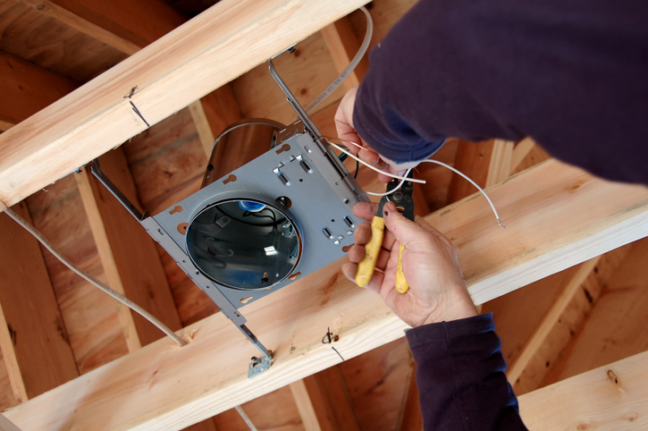 Electrician installing lighting box in home under construction